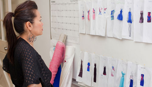 Project Runaway Star Chloe Dao looking at design sketches